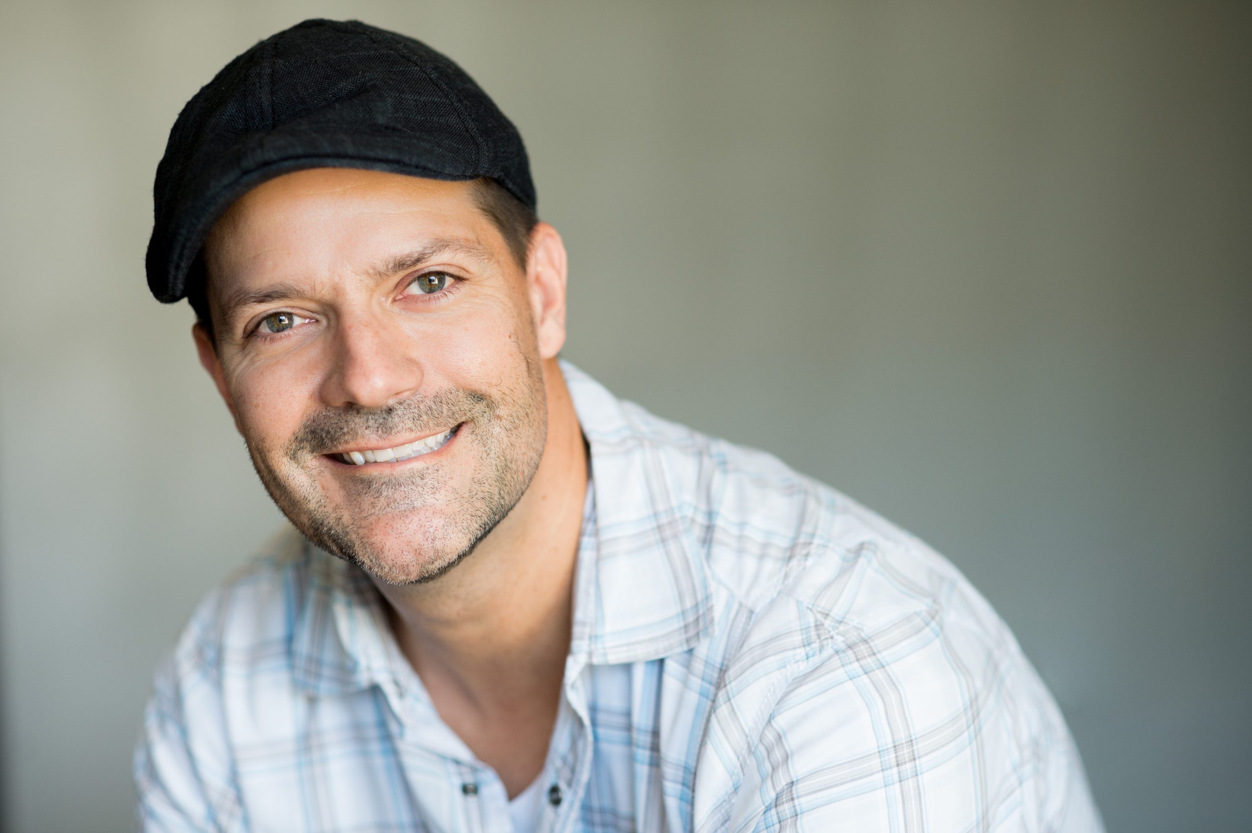 Lee Dyson smiling in a flat cap and a pale checked shirt.