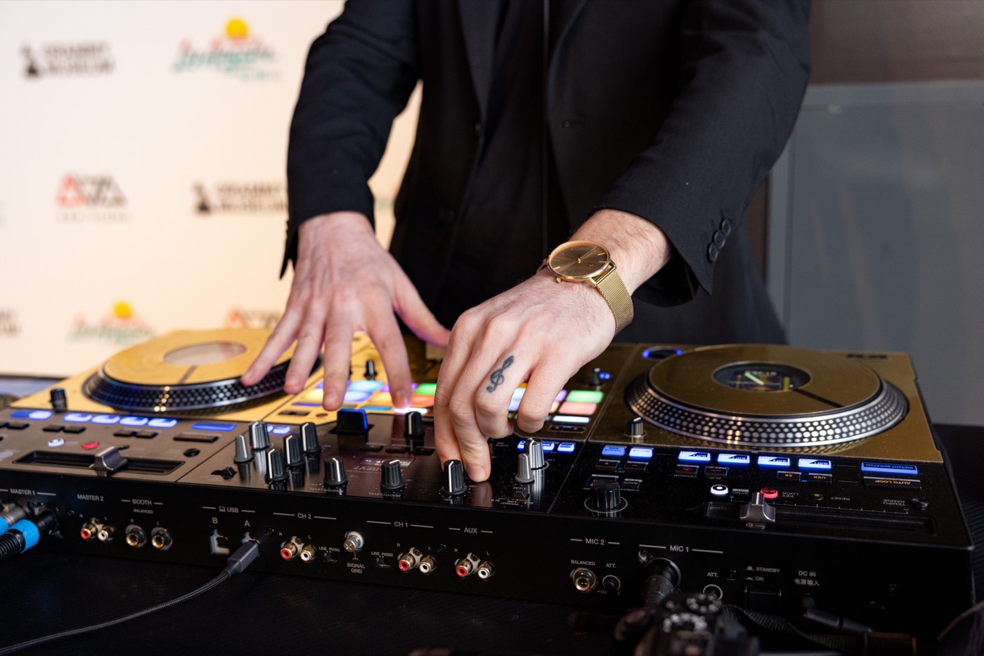 Two hands working a mixer between two gold turntables.